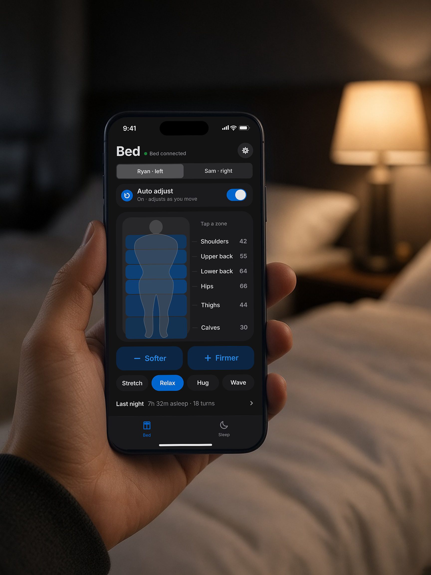 A hand holding a phone showing the Sensio Sleep app at the bedside